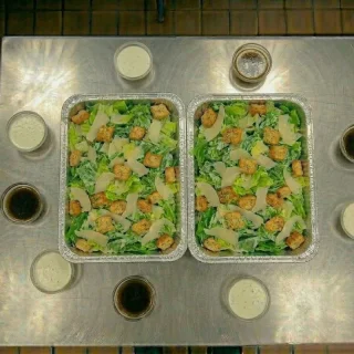 Caesar salad catering trays with romaine lettuce, croutons, shaved parmesan, and Caesar dressing at Ally’s Comfort Café in Davie, FL