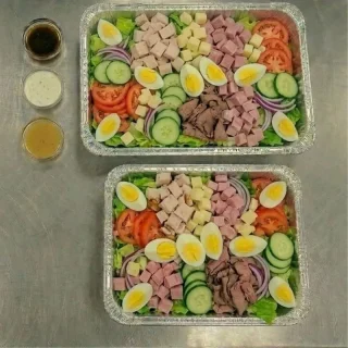Chef’s salad catering trays with romaine, turkey, ham, roast beef, Swiss cheese, tomatoes, cucumbers, onions, and hard-boiled eggs at Ally’s Comfort Café in Davie, FL