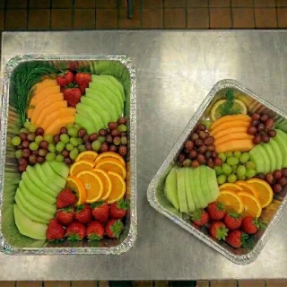 Fresh fruit platter catering trays with cantaloupe, honeydew, grapes, oranges, and strawberries at Ally’s Comfort Café in Davie, FL