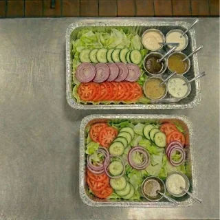 House salad catering trays with iceberg lettuce, tomatoes, red onions, cucumbers, and assorted dressings at Ally’s Comfort Café in Davie, FL