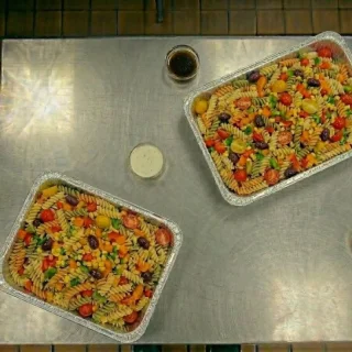 Pasta salad catering tray with rotini pasta, cherry tomatoes, bell peppers, kalamata olives, and corn at Ally’s Comfort Café in Davie, FL